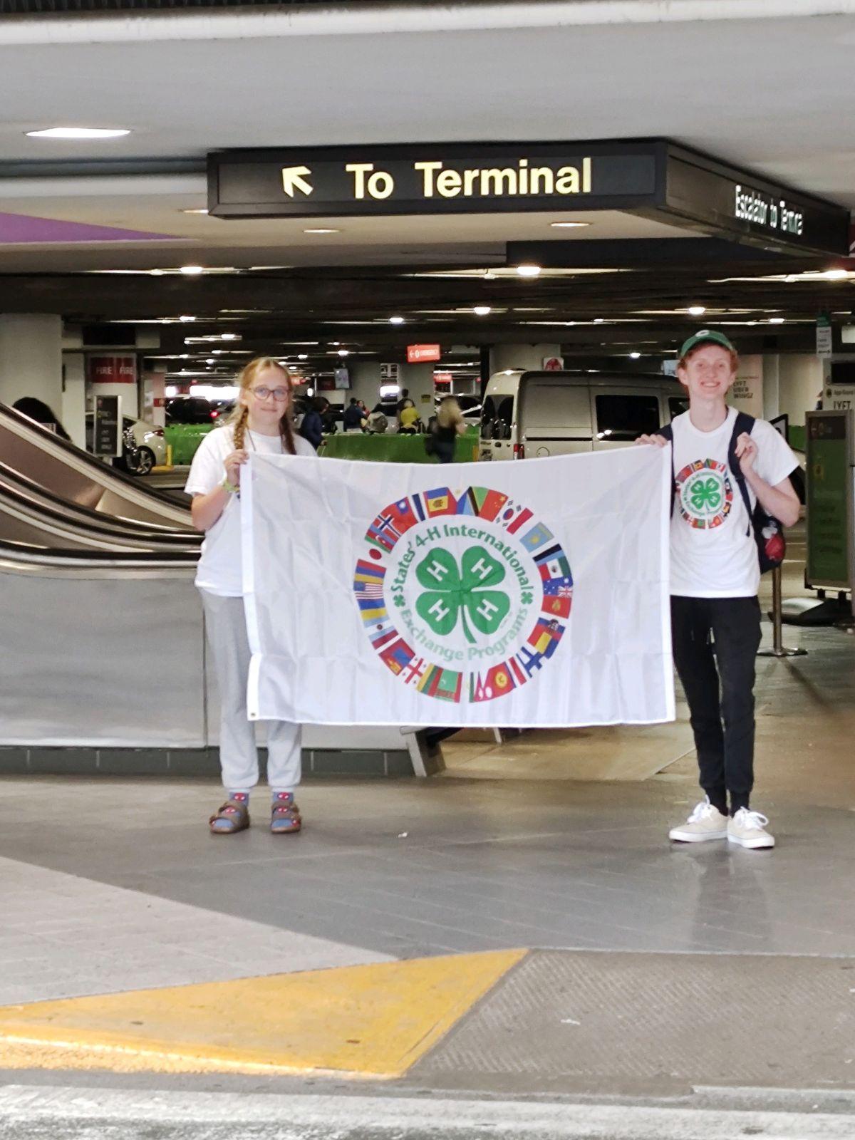 Lily and Daniel hold the States' 4-H flag at the airport.